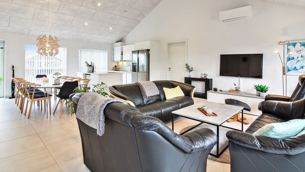 Een ruime woonkamer met een moderne keuken, een eethoek en een zithoek met leren banken en een salontafel.