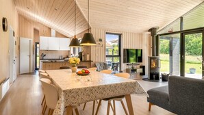 Un interior moderno con comedor, cocina y chimenea.