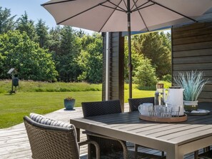 A wooden deck with a table and chairs, a large umbrella, and a bird feeder. - "Dyke" - 1.5km from the sea by Interhome (Saltum)