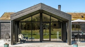 Una casa moderna con un porche cubierto, ventanas amplias y una chimenea.