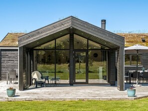 A modern house with a covered patio, large windows, and a chimney. - "Dyke" - 1.5km from the sea by Interhome (Saltum)
