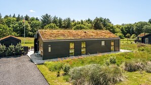 Un edificio moderno con techo inclinado, número 11, rodeado de vegetación y otras construcciones.