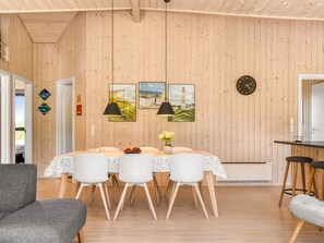 A dining area with a wooden wall, a dining table with white chairs, and two pendant lights. - "Dyke" - 1.5km from the sea by Interhome (Saltum)
