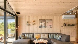 Una sala de estar moderna con un sofá seccional gris, una mesa redonda de centro y un ventanal con vistas al exterior.