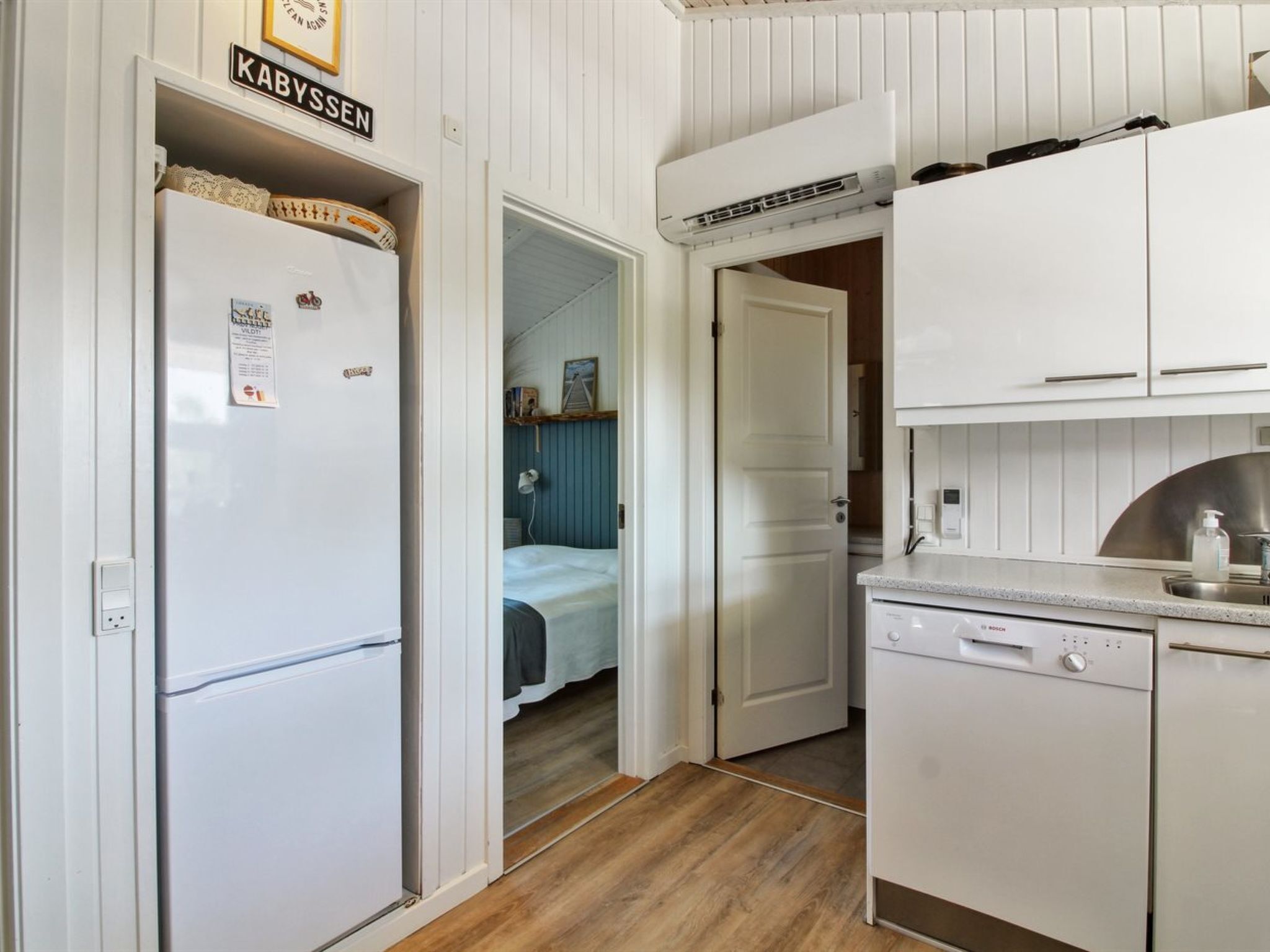 A compact kitchen with white cabinetry, a Bosch dishwasher, and a door labeled "KABYSSEN".