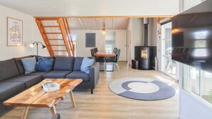 Una sala de estar moderna con sofá, mesa de centro y comedor con sillas.