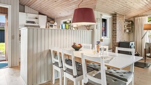 A modern kitchen with white cabinetry, a dining table with chairs, and a red pendant light. - "Apsolon" - 600m from the sea by Interhome (Løkken)