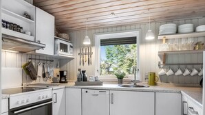 A modern kitchen with white cabinetry, a built-in oven, a dishwasher, and a window providing natural light. - "Apsolon" - 600m from the sea by Interhome (Løkken)