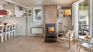 A cozy room with a brick fireplace, wooden ceiling, and a dining area with a table and chairs. - "Apsolon" - 600m from the sea by Interhome (Løkken)