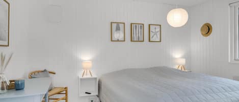Un dormitorio con cama, mesitas de noche, un escritorio y una obra de arte en la pared.