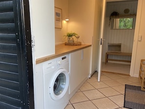 A compact laundry area with a Siemens washing machine, a small wooden counter, and a door leading to a room with a bench and a window. - "Barba" - 2km from the sea by Interhome (Blokhus)