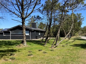 A modern house with a garage, surrounded by trees and grass.