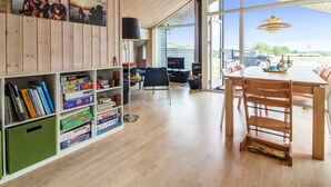 A spacious room with wooden walls, a large dining table, and a bookshelf filled with books. - "Alma" - 500m from the sea by Interhome (Løkken)