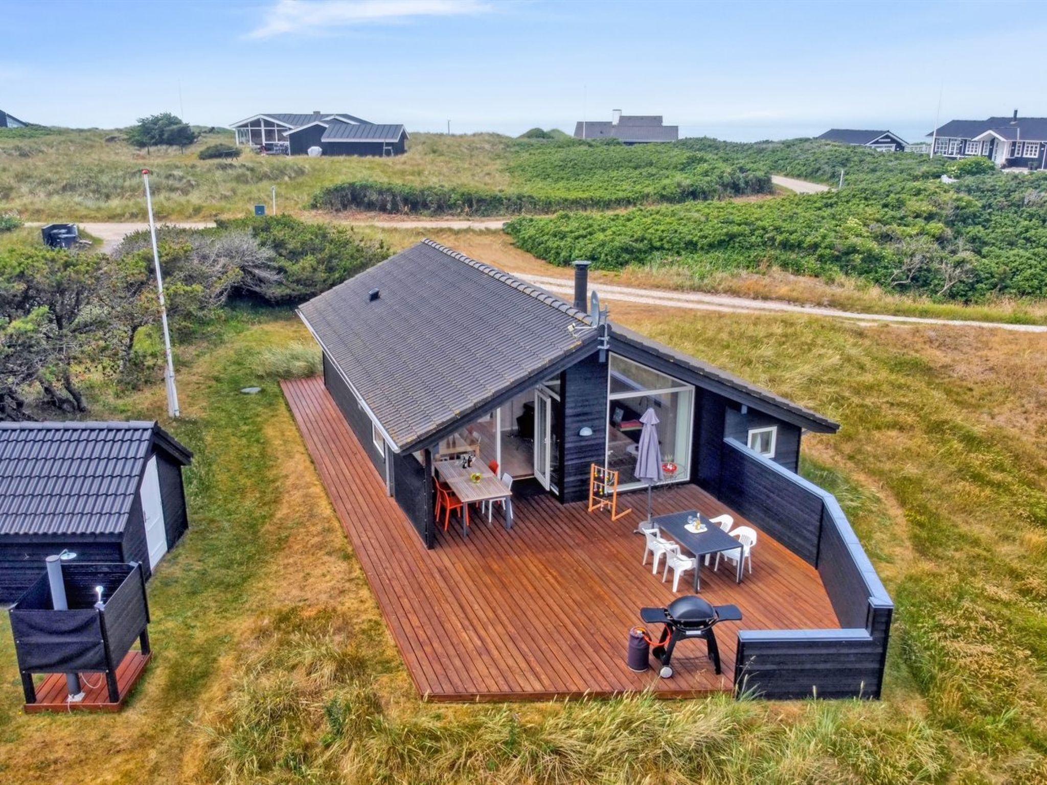 A modern house with a wooden deck, a barbecue area, and a view of the surrounding landscape.