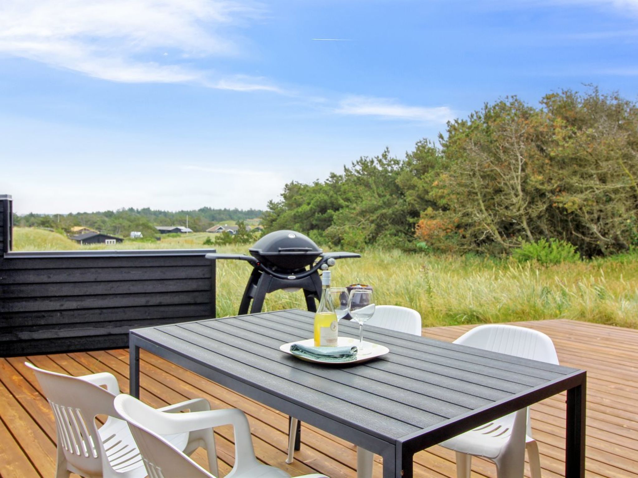 Une terrasse extérieure avec une table et des chaises, un barbecue et une vue panoramique sur la campagne.