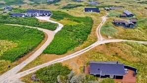 An aerial view of a coastal area with houses surrounded by greenery, featuring winding roads and a beach in the background. - "Alma" - 500m from the sea by Interhome (Løkken)