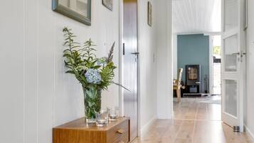 Un couloir avec une console en bois, un vase de fleurs et un miroir.