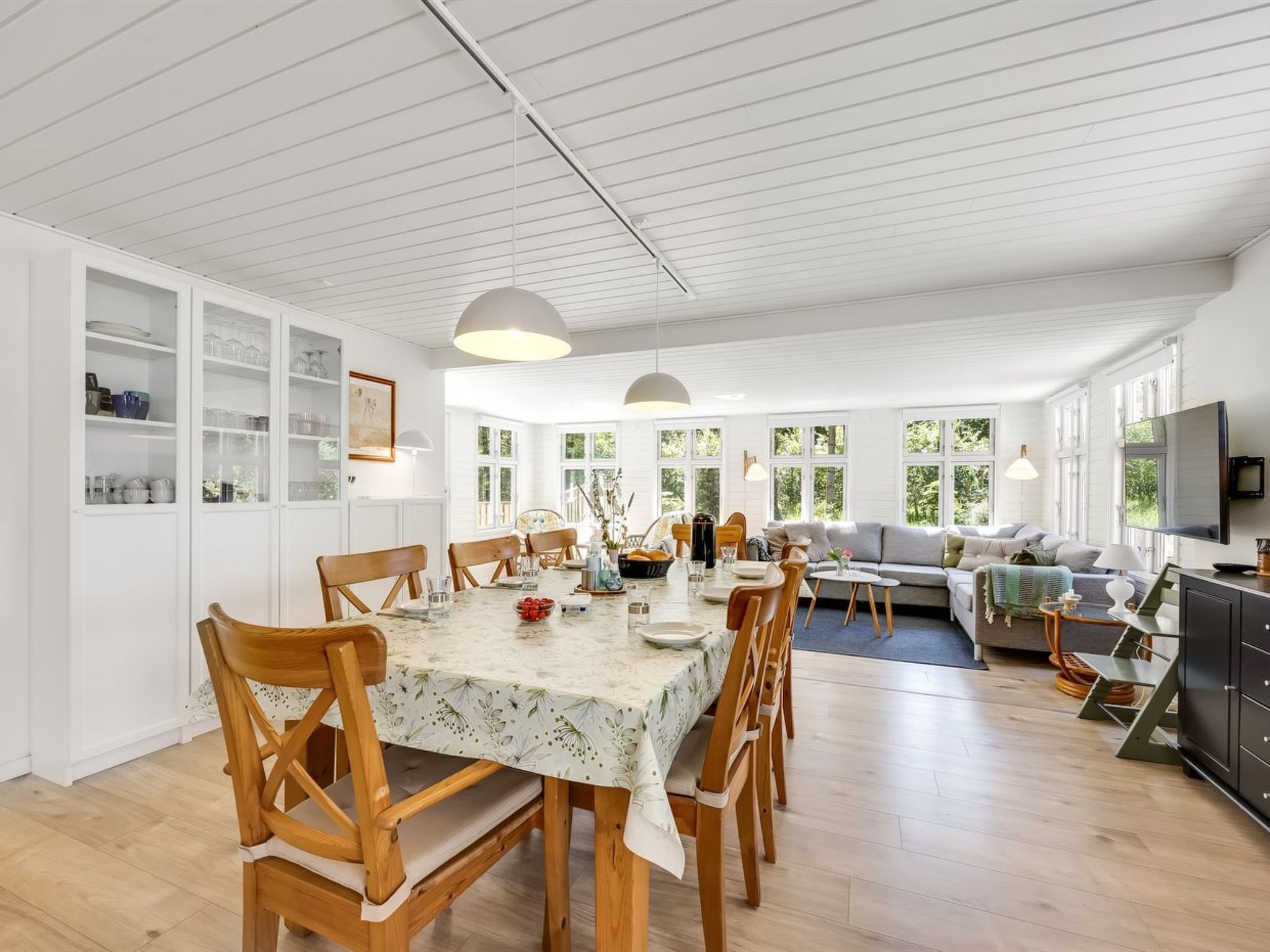 Un grand espace de vie comprenant une table à manger, des chaises en bois, un canapé et un téléviseur.