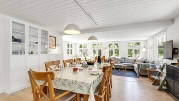 Un grand espace de vie comprenant une table à manger, des chaises en bois, un canapé et un téléviseur.