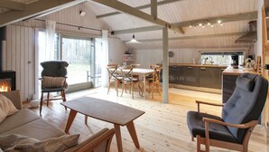 Een ruime woonkamer met een open haard, houten meubels en uitzicht op de omgeving.