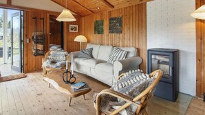 A cozy living room with a wooden ceiling, a sofa, two wicker chairs, a coffee table, and a fireplace. - "Nestori" - 950m from the sea by Interhome (Løkken)