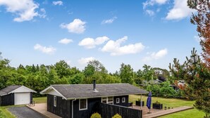 Een klein vakantiehuisje met een metalen dak, een veranda en een klein terras.