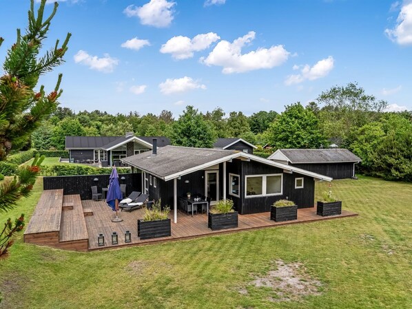 Une maison moderne dotée d’un patio, d’un espace salon extérieur et d’une pelouse bien entretenue.