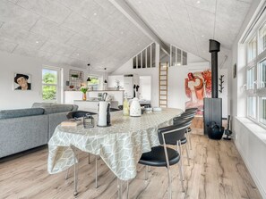 A modern kitchen with a dining area, a large window, and a painting on the wall.
