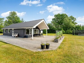A modern house with a covered patio, a deck, and a garden area.
