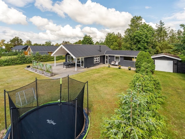 A residential property with a trampoline, a covered patio, and a garage.