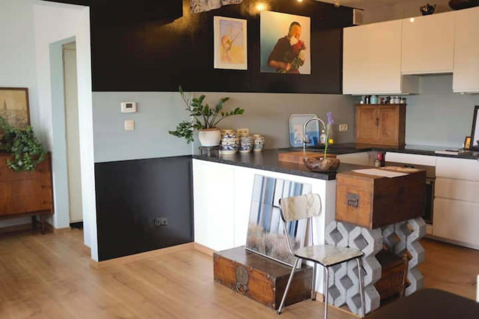 A modern kitchen with a black and white color scheme, wooden cabinets, a central island, and a potted plant.