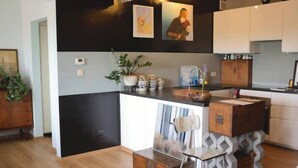 Uma cozinha moderna com esquema de cores preto e branco, armários de madeira, uma ilha central e um vaso com planta.