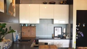 Cozinha moderna com armários brancos, bancada de madeira e uma pia.
