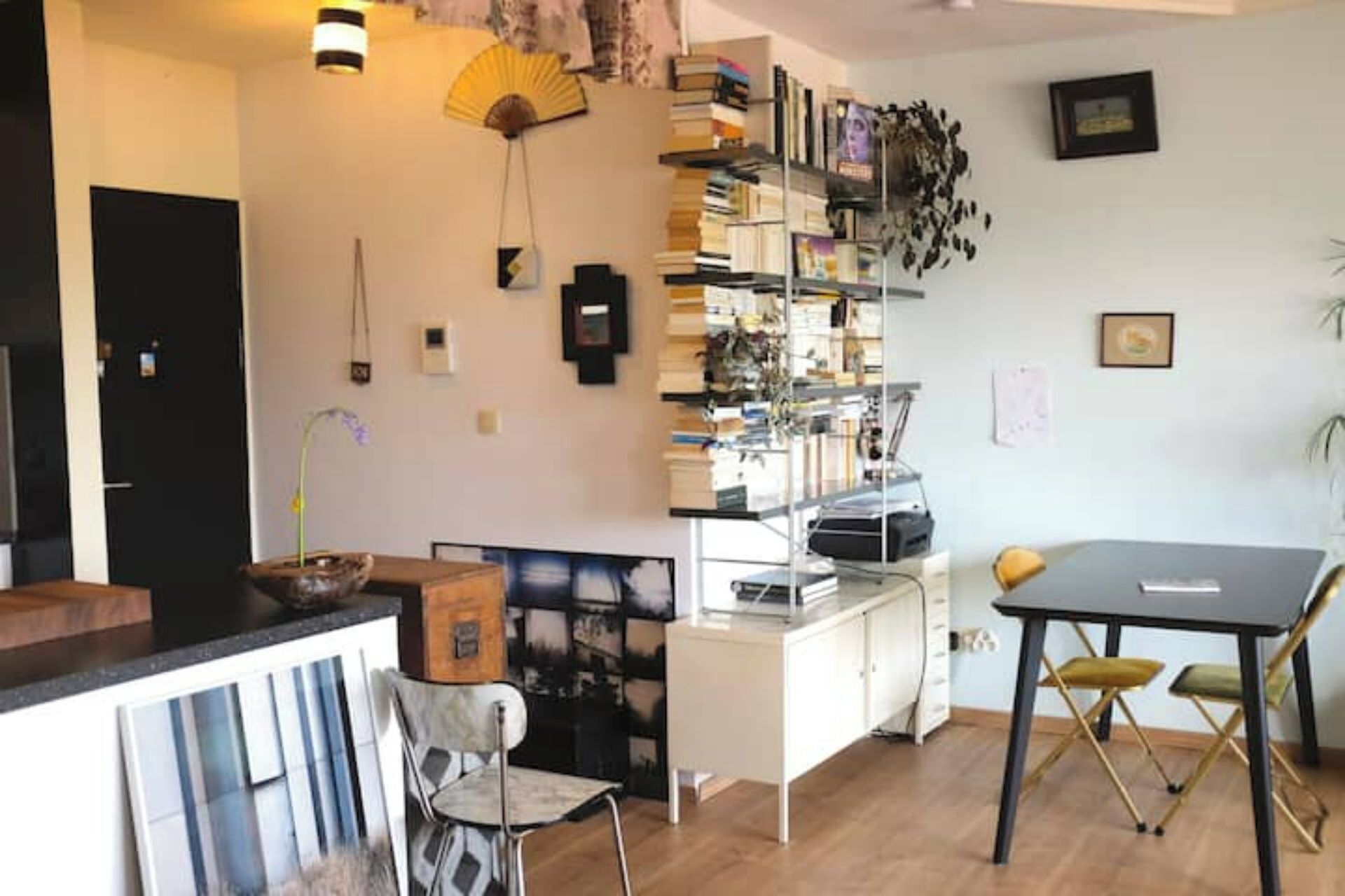 Un salon moderne avec un bureau blanc, une bibliothèque et un coin repas avec des chaises.