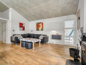 Una sala de estar moderna con un sofá de cuero negro, una mesa de comedor de madera y un horno para pizza.