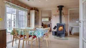 L’intérieur d’un chalet chaleureux, avec un coin repas, une cheminée et des murs en bois.