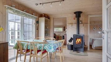L’intérieur d’un chalet chaleureux, avec un coin repas, une cheminée et des murs en bois.