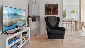A living room with a TV, bookshelves, a chair, and a wooden floor. - "Aris" - 480m from the sea by Interhome (Ebeltoft)