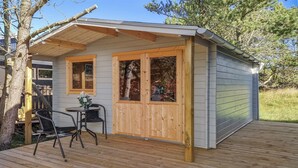 Una pequeña cabaña de madera con un balcón, una mesa y sillas.