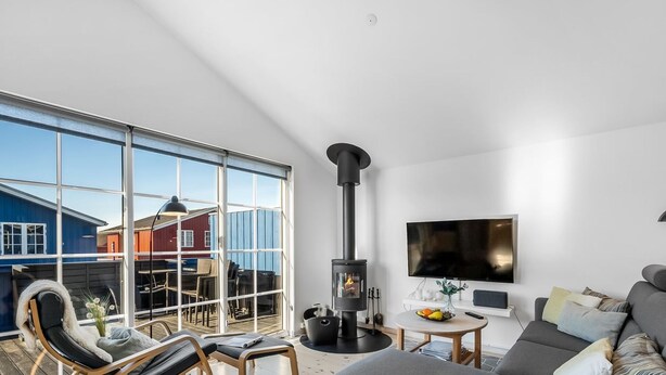 Una sala de estar moderna con un ventanal grande, chimenea, sofá y televisor.