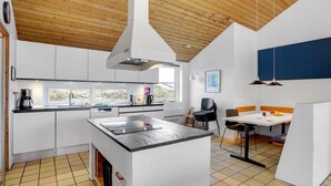Una cocina moderna con armarios blancos, una isla central y un comedor con mesa y sillas.