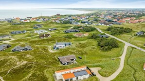 Vista aérea de una zona residencial costera con casas, calles y una playa al fondo.