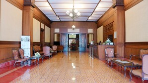 Un hall de hotel con mostrador de recepción, zona de estar y una lámpara de araña.