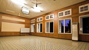 Un espacio amplio con piso estampado, paredes de madera y varias ventanas.