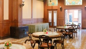 Un comedor con mesas y sillas redondas, paneles de madera y suelo estampado.