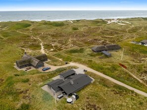 A coastal property with multiple buildings, a dirt path, and a view of the ocean.