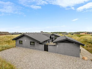 Ein modernes Haus mit grauem Anstrich, einem Schotterweg und blauem Himmel.