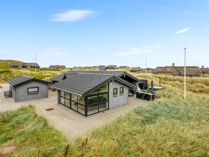 A modern house with a flat roof, large windows, and a patio area.