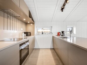 A modern kitchen with a central island, built-in appliances, and a view of a natural landscape through a window.