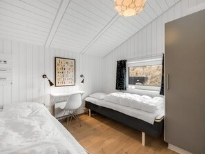 Ein Schlafzimmer mit Bett, Schreibtisch und einem Vorhangfenster.